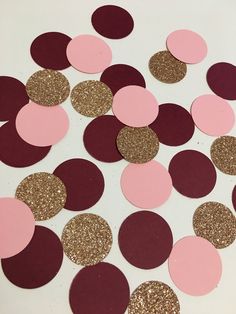 some pink and gold confetti on a white table with glitter circles around it