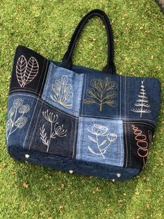 a handbag made out of jeans with trees and leaves painted on the front pocket