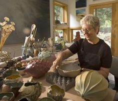 a woman sitting at a table with many bowls and plates on top of the table