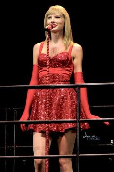 a woman in red dress standing on top of a stage