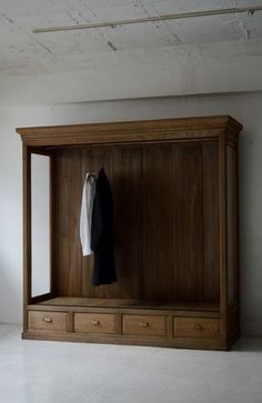 an open wooden closet with clothes hanging on it