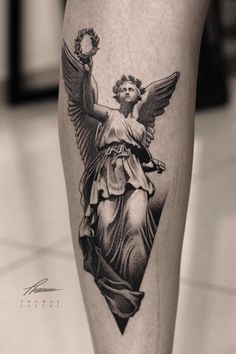 a black and white photo of an angel tattoo on the leg