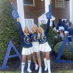 two girls in cheerleader outfits holding up signs