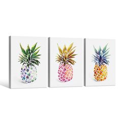 three colorful pineapples on white canvases mounted to the side of a wall