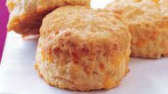 some biscuits are sitting on top of a white paper towel and pink background, with the rest of the biscuits visible in the foreground