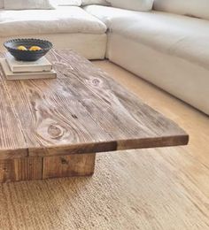 a wooden table sitting in the middle of a living room next to a white couch