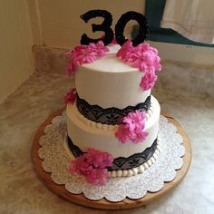 a three tiered cake decorated with pink flowers and the number 30 on it's side