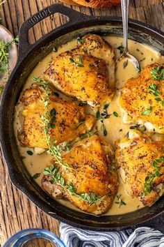 chicken with gravy in a cast iron skillet on a wooden table next to bread