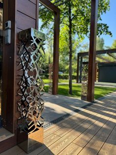 an outdoor sculpture on the side of a wooden building with trees in the back ground