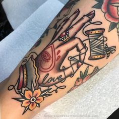 a woman's arm with tattoos on it and an image of a hand holding a spool of thread