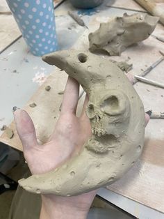 a person is holding a clay skull and half - moon shaped object in their hand