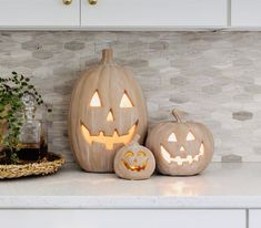 three carved pumpkins sitting on top of a kitchen counter