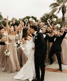 a bride and groom kissing in front of their wedding party