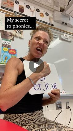 a woman holding up a sign in front of a whiteboard