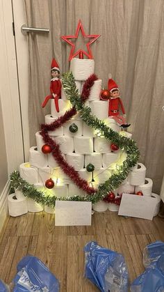 a christmas tree made out of toilet paper and wrapped in plastic wrap with decorations around it