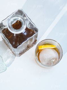 two glasses filled with liquid sitting next to each other on a white counter top and one has a slice of lemon in it