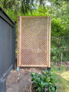 a wooden gate in the middle of a yard next to a planter filled with flowers