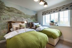 two beds in a room with green comforters and pillows on them, next to a window