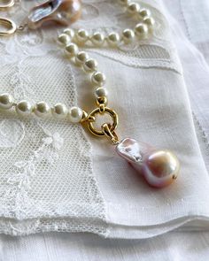 This hand-knotted pearl shell necklace features a charming baroque pearl charm, perfect for adding some whimsy to your wardrobe. At 16 inches in length, it's a versatile piece that can be dressed up or down for any occasion. Embrace your playful side with Geniva Pearls! Baroque Pearl Bracelet With Pendant For Wedding, Pearl White Necklace With Pearl Charm, Wedding Pearl Bracelet With Baroque Pendant, Wedding Pearl Bracelet With Baroque Pearl Pendant, Gift Pearl Necklace With Lobster Clasp, Pearl White Pearl Necklace With Charm, Baroque Pearl Necklace With Lobster Clasp As Gift, Pearl Pendant Necklace With Lobster Clasp, Pearl White Pearl Necklaces With Lobster Clasp