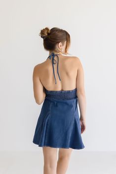 Flaunt your playful style in the Anita Mini Dress. This sleeveless halter dress features a deep neckline with a flirty halter tie and smocked back panel for a comfortable fit. The flared skirt in dark wash denim with contrast stitching adds a touch of uniqueness to your look. Perfect for any fun occasion! Details + Fit 100% Polyester Runs True to Size Hand Wash Cold Hang Dry Plunging Neckline Halter Tie Sleeveless Smocked Back Panel Flared Skirt Contrast Stitching Denim Design Dark Wash | Solid Model is 5’4” and wearing a size Small Fitted Mini Dress With Elastic Neckline For Day Out, Chic Fitted Halter Dress With Elastic Neckline, Flirty Halter Neck Dress With Smocked Back, Halter Neck Dress With Tie Back For Brunch, Flirty Halter Neck Dress With Ruched Back, Brunch Halter Neck Dress With Tie Back, Brunch Halter Dress With Tie Back, Sleeveless Tie Back Halter Top For Brunch, Chic Sundress With Elastic Neckline