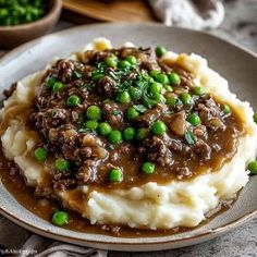 a plate with mashed potatoes, peas and gravy