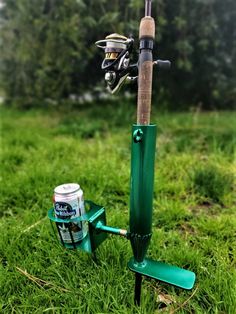 a fishing rod and reel stand in the grass next to a can of beer on a pole