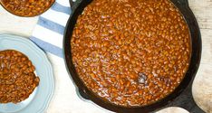 baked beans in a cast iron skillet on a table with two plates next to it