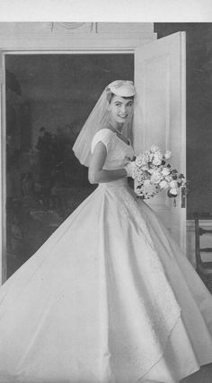 an old black and white photo of a woman in a wedding dress holding a bouquet