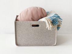 a gray storage bin with a pink pillow and throw pillows in it on a white surface