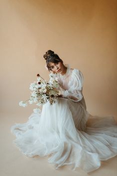 a woman in a white dress holding a bouquet of flowers