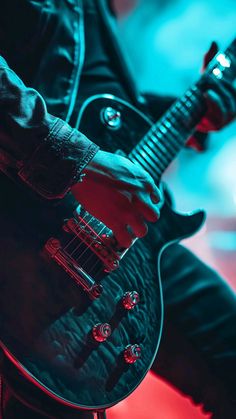 a man is playing an electric guitar in the dark with red light from behind him