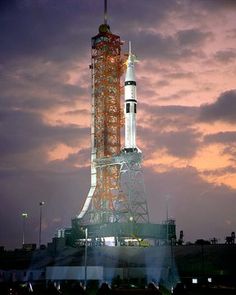 an image of a rocket that is on the ground at night time with clouds in the background