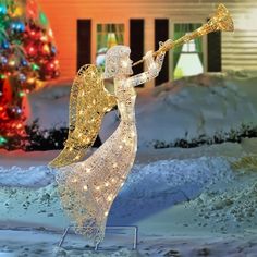 a lighted angel playing the trumpet in front of a christmas tree