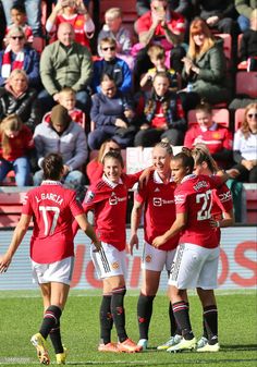 a group of women in red soccer uniforms standing on a field with their arms around each other