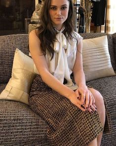 a woman sitting on top of a couch wearing a skirt