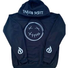 This Is The Travis Scott Hoodie With Dead Smile Face Design On The Front And La Flame Design On The Sleeves And Name On Hood On A Black Hoodie With White Print. Black Sweatshirt With Double-lined Hood For Urban Adventures, Logo Print Hoodie For Fall, Hip Hop Black Hoodie For Fall, Black Hip Hop Hoodie For Fall, Black Hoodie With Logo Print, Black Hooded Outerwear With Logo Print, Trendy Black Sweatshirt For Urban Adventures, Travis Scott Hoodie, Light Grey Hoodie