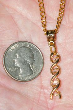 a tiny gold necklace with the word love written on it next to a dime in someone's hand