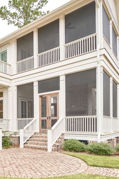 a white house with two balconies on the second floor and stairs leading up to it