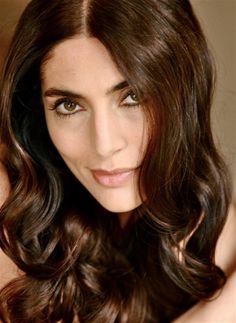 a beautiful woman with long brown hair posing for the camera