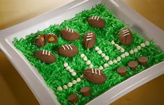 a cake made to look like grass with footballs and cupcakes on it