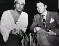 two men sitting next to each other in front of a black and white photo with one man wearing a turban