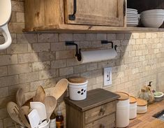 a kitchen with wooden cabinets and lots of utensils on the counter top in front of it