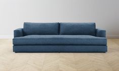 a blue couch sitting on top of a hard wood floor next to a white wall