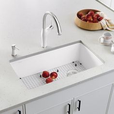 a white sink sitting on top of a kitchen counter next to a bowl of fruit