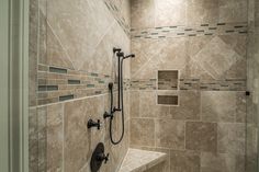 a walk in shower sitting next to a tiled wall and floor covered in beige tiles