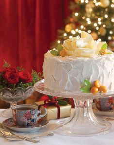 a white cake sitting on top of a table next to a cup and saucer