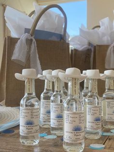 six bottles of water sitting on top of a wooden table next to a brown bag