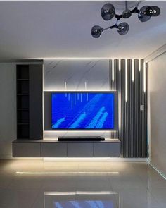 a modern living room with a large tv on the wall and lights hanging from the ceiling