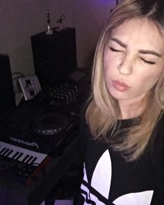 a woman with her eyes closed standing in front of an electronic keyboard and mixing equipment