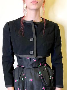 "This is great black wool cropped jacket by designer Geoffrey Beene! Buttons up the front and has a grosgrain ribbon trim. Fully lined with a satiny lining.  Really a great designer jacket! The quality and craftsmanship is certainly shown in the way the button holes are finished and the exquisite couture cut of the jacket.  This was made in the early part of the designers label, early to mid 1960s. Measurements are approximately:  36\" bust  13.5\" in length from back collar to hem 15\" across t Fitted Black Silk Outerwear, Fitted Wool Cropped Jacket For Spring, Tailored Black Cropped Jacket For Evening, Black Tailored Cropped Jacket For Evening, Spring Wool Cropped Jacket, Spring Cropped Wool Jacket, Spring Evening Cropped Outerwear, Tailored Cropped Jacket For Evening In Spring, Jacket Fabric